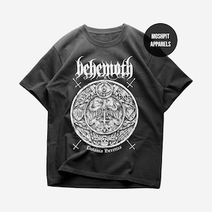 May include: Black t-shirt featuring a white graphic design. The design includes the word "Behemoth" in gothic lettering above a circular emblem with intricate details, crosses, and the text "Polonia Heretica". A "Moshpit Apparels" logo is visible.