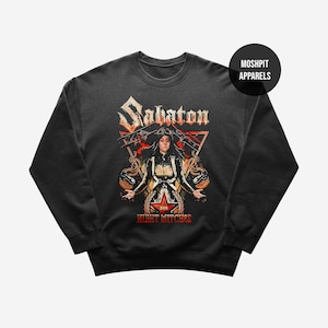 Könnte beinhalten: Dunkelgraues Sweatshirt mit einem Aufdruck einer Frau, einem Stern und den Worten "Sabaton" und "Night Witches" in Rot und Gold. Das Sweatshirt hat einen Rundhalsausschnitt und lange Ärmel.