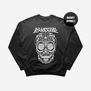 May include: Black crewneck sweatshirt featuring a detailed white skull design. The skull is intricately patterned with floral and ornamental elements. The text "KILLSWITCH ENGAGE" is displayed above the skull in a stylized font. The brand "MOSHPIT APPARELS" is also visible.