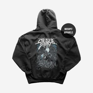 Puede incluir: Sudadera con capucha gris oscuro con un gráfico de una parca con grandes alas y el nombre de la banda "Chelsea Grin" en blanco. La sudadera con capucha tiene una capucha y un bolsillo delantero. La marca "Moshpit Apparels" está impresa en la parte superior derecha.