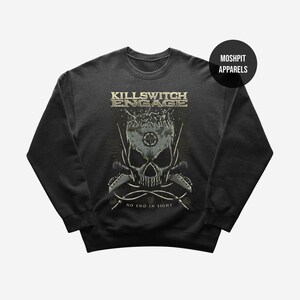 May include: Dark gray sweatshirt featuring a skull graphic with crossed swords and the text "KILLSWITCH ENGAGE" above and "NO END IN SIGHT" below. The design is in shades of gray and beige. The brand name "MOSHPIT APPARELS" is in a black circle.