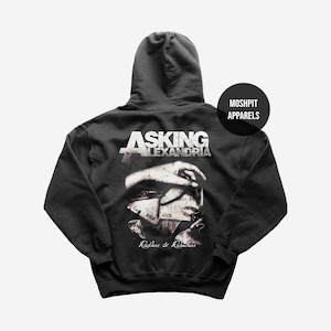 May include: Black hooded sweatshirt featuring the band name "Asking Alexandria" in white, with a graphic of a hand and a face. The text "Reckless & Relentless" is below the graphic. The brand name "Moshpit Apparels" is on the right.