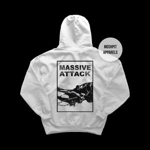 Könnte beinhalten: Weißer Kapuzenpullover mit dem Text "MASSIVE ATTACK" in einem schwarzen Rechteck auf dem Rücken. Darunter befindet sich eine schwarz-weiße Grafik. Der Markenname "MOSHPIT APPARELS" ist oben rechts zu sehen.