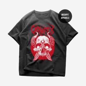May include: Dark grey t-shirt with a red and white skull graphic, horns, and a third eye, set on a red circle. The word "CRIMSON" is above the skull. The shirt has a round neck and short sleeves. The brand name "MOSHPIT APPARELS" is on the upper right.