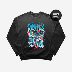 May include: Black crew neck sweatshirt with a graphic design. The design features the word "CARNIFEX" in blue, and a zombie-themed illustration in white, red, and blue. The sweatshirt has a round neckline and long sleeves. The brand name "MOSHPIT APPARELS" is in a black circle.