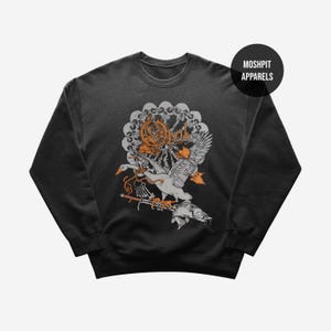 Puede incluir: Sudadera gris oscuro con un diseño gráfico que presenta un cisne, un pez y calaveras. El diseño incluye la palabra "Opeth" en letras naranjas. La sudadera tiene cuello redondo y mangas largas. La marca "Moshpit Apparels" está impresa en un círculo negro.