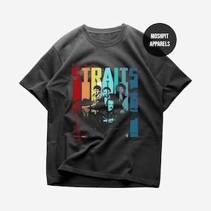 Pode incluir: T-shirt cinzento escuro com um gráfico colorido da banda Dire Straits. O nome da banda é exibido em letras grandes e multicoloridas acima de uma silhueta dos membros da banda. A camisa tem gola redonda e mangas curtas.