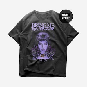 May include: Dark gray t-shirt featuring a graphic of a woman with a lion headdress, purple roses, and an eye within a triangle. The text "BRING ME THE HORIZON" is above the graphic. The shirt has a round neck and short sleeves.