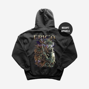 May include: Dark gray hoodie with a detailed graphic on the back featuring a figure with a staff, a wolf, and the word "ERICA" in gold lettering. The hoodie has a hood and a round label that says "MOSHPIT APPARELS".