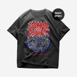 May include: Dark gray t-shirt featuring a red and white graphic with the text "MORBID ANGEL" above a blue and white illustration. The text "ALTARS OF MADNESS" is below the illustration. The shirt has a round neckline and short sleeves.