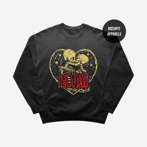 May include: Black crew neck sweatshirt with a heart-shaped design featuring two skeletons in gold and red. The word "INCUBUS" is in red. The brand name "MOSHPIT APPARELS" is in a black circle on the top right.
