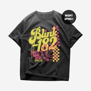 May include: Dark gray t-shirt featuring the band name "Blink 182" in yellow graffiti-style lettering. The shirt also includes the text "Crappy Punk Rock Since '92" in pink, along with a pink and yellow checkered design.
