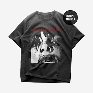 May include: Dark grey t-shirt with a black and white face graphic and red text reading "my bloody Valentine". A black circle with "MOSHPIT APPARELS" is in the upper right. The t-shirt is a casual wear item.