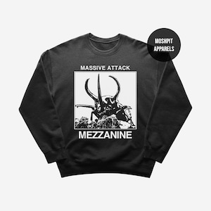 Könnte beinhalten: Dunkelgraues Sweatshirt mit einer schwarz-weißen Grafik eines Käfers, dem Text "MASSIVE ATTACK" darüber und "MEZZANINE" darunter. Das Sweatshirt hat einen Rundhalsausschnitt und lange Ärmel. Der Markenname "MOSHPIT APPARELS" befindet sich in einem schwarzen Kreis oben rechts.