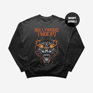 May include: Dark gray sweatshirt featuring a detailed illustration of a snarling wolf's head with fiery orange accents. The text "HOLLYWOOD UNDEAD" is printed above the wolf in orange. The sweatshirt has a crew neck and long sleeves.