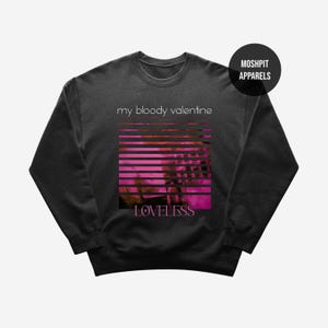 May include: Charcoal grey sweatshirt with the words "my bloody valentine" above a pink and orange striped design. The word "LOVELESS" is below the graphic. A black circle with "MOSHPIT APPARELS" in white is in the top right.