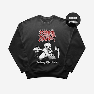 May include: Black crew neck sweatshirt with a white graphic of a skull playing a wind instrument, and the text "LEADING THE RATS" below. The top of the sweatshirt has the red text "MORBID ANGEL". The brand name "MOSHPIT APPARELS" is in a black circle.