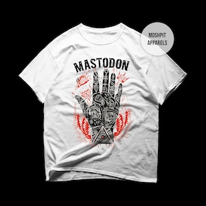 May include: White t-shirt featuring a detailed black and red graphic of a hand with various symbols and the band name "MASTODON" above it. The design includes a red wing-like element at the bottom. The shirt is from Moshpit Apparels.