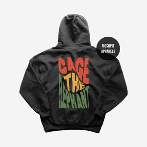 May include: Black hooded sweatshirt with the text "CAGE THE ELEPHANT" in red, yellow, and green. The sweatshirt has a drawstring hood and a kangaroo pocket. The brand name "MOSHPIT APPARELS" is printed on a black circle.