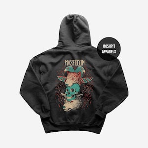 May include: Dark gray hoodie featuring a stacked graphic of a tiger, skull, and wolf with the word "MASTODON" above. The graphic is in shades of red, teal, and beige. The hoodie has a hood and a "MOSH PIT APPARELS" logo.