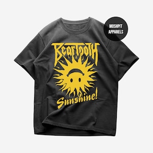 May include: Dark grey t-shirt with a yellow graphic of a smiling sun and the word "Sunshine!" below. The band name "Beartooth" is printed above the sun in yellow. The shirt has a crew neck and short sleeves.