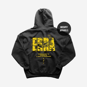 Könnte beinhalten: Dunkelgrauer Kapuzenpullover mit gelbem Grafikdesign auf der Rückseite. Das Design enthält das Wort "ERA" und die Sätze "SHADOWS WAIT TO DEVOUR US" und "IT HURTS TO SURRENDER". Der Hoodie hat auch den Text "ネオン".
