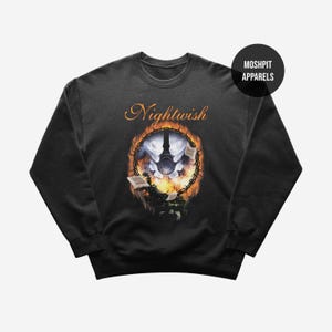 May include: Black crewneck sweatshirt featuring the band name "Nightwish" in gold script above a circular graphic. The graphic includes a central image with a moon, books, and flames, with the text "Moshpit Apparels" in a black circle.