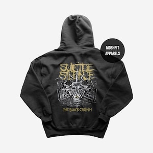 Könnte beinhalten: Dunkelgrauer Kapuzenpullover mit einem grafischen Design auf dem Rücken. Das Design zeigt die Worte "SUICIDE SILENCE" in goldfarbenen Buchstaben über einer detaillierten Illustration eines Skeletts und anderer Elemente. Der Text "THE BLACK CROWN" steht darunter.