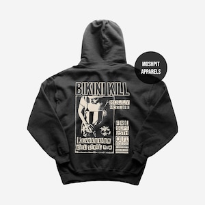 Może przedstawiać: Czarna bluza z kapturem z grafiką zespołu Bikini Kill. Projekt zawiera nazwę zespołu, nazwisko Molly McGuire oraz słowa "Revolution Girl Style Now". Bluza z kapturem ma również napis "Fri. Sept 25th" i markę "Moshpit Apparels".