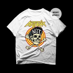 May include: White t-shirt with the yellow "Anthrax" logo and a skull wearing a black hat with "NOT" on it. The skull is set against a red and yellow target, with crossed bones. The text "Moshpit Apparels" is printed on the top right of the shirt.