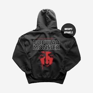May include: Dark grey hooded sweatshirt with the text "POPULAR MONSTER" in white, above a red graphic of a face. The sweatshirt also features the text "FALLING IN REVERSE" and a black circle with the text "MOSHPIT APPARELS".