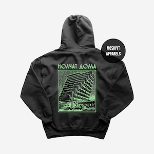 May include: Dark grey hoodie featuring a green graphic of a building and the Cyrillic text "Молчат Дома". A black circle on the right side reads "Moshpit Apparels". The hoodie has a hood and a front pocket.