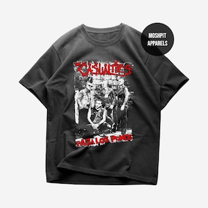 May include: Dark grey t-shirt with a black and white band graphic and red text reading "CASUALTIES" above and "PARA LOS PUNKS" below. The shirt has a crew neck and short sleeves, a classic punk rock design.