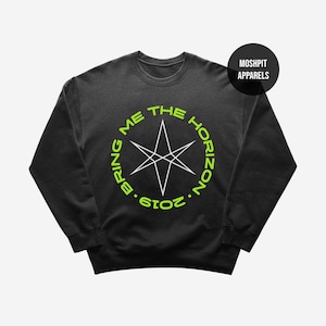 May include: Black crewneck sweatshirt with a neon green and white graphic. The graphic features a starburst design inside a circle with the text "BRING ME THE HORIZON 2019". A black circle with "MOSHPIT APPARELS" is in the upper right corner.
