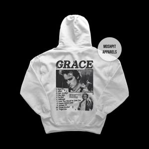 Op de afbeelding: Een lichtgrijze hoodie met de albumhoes van "Grace". De achterkant van de hoodie toont een zwart-wit afbeelding van de artiest, de albumtitel en een tracklist. De merknaam "MOSHPIT APPARELS" staat rechtsboven.