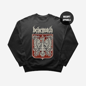May include: Dark gray sweatshirt featuring a red and white graphic. The graphic includes the word "behemoth" in a gothic font above a shield design with a cross, snakes, and wings. The brand name "Moshpit Apparels" is in a black circle.