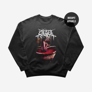 Puede incluir: Sudadera gris oscuro con un gráfico de una persona en una bañera llena de líquido rojo. El nombre de la banda "Chelsea Grin" se muestra en texto blanco estilizado encima de la imagen. El logotipo de la marca "Moshpit Apparels" está en la esquina superior derecha.
