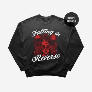 May include: Dark grey sweatshirt with a graphic design featuring a red skull, skeleton hands covering a woman's eyes, and the text "Falling in Reverse" in white. The sweatshirt has a crew neck and long sleeves.