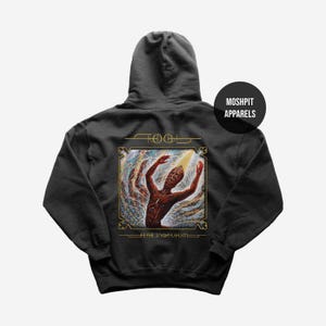 Puede incluir: Sudadera con capucha gris oscuro con un diseño gráfico de la banda Tool. El diseño presenta una figura con los brazos levantados, dentro de una ilustración enmarcada en oro. También se ve el texto "TOOL" y "FEAR INOCULUM". La sudadera tiene capucha y un logotipo redondo que dice "MOSHPIT APPARELS".