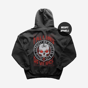 May include: Dark grey hoodie with a red and white skull graphic and the text "Falling Straight to Hell for Me in Reverse." The hoodie has a drawstring hood and a kangaroo pocket. The brand name "Moshpit Apparels" is printed on the upper right.
