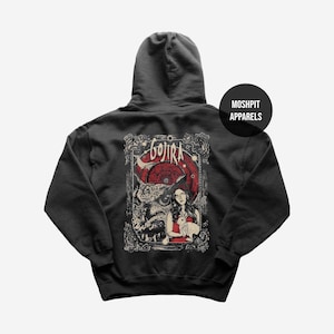 May include: Dark gray hoodie featuring a graphic design on the back. The design includes the word "GOJIRA" in a stylized font, a woman in a red dress, and a rabbit. The hoodie has a hood and a "MOSHPIT APPARELS" logo.