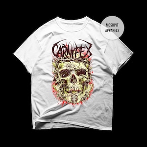 May include: White t-shirt with a detailed skull graphic and the word "CARNIFEX" above it. The skull is yellow and green with red accents. The shirt has the text "MOSHPIT APPARELS" on the upper right.