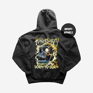 May include: Black hooded sweatshirt featuring a colorful skull graphic with the text "HALESTORM" and "BORN TO BURN". The design includes yellow, blue, and orange flames around the skull. The brand "MOSHPIT APPARELS" is also visible.
