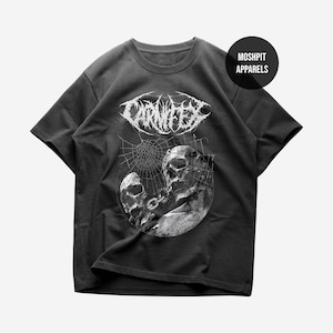 Puede incluir: Camiseta gris oscuro con un gráfico blanco de dos calaveras conectadas por una cadena, con un diseño de telaraña. La palabra "CARNIFEX" está impresa encima de las calaveras en una fuente estilizada. La camiseta también tiene el texto "MOSHPIT APPARELS" en un círculo.