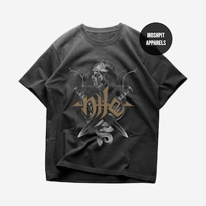 Puede incluir: Camiseta gris oscuro con un diseño de calavera, cuchillos cruzados y una serpiente en tonos grises y dorados. El texto "Moshpit Apparels" está en un círculo negro en la parte superior derecha.