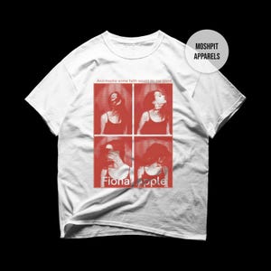 Puede incluir: Camiseta blanca con un gráfico rojo de cuatro imágenes de una persona, el texto "Fiona Apple" y la frase "And maybe some faith would do me good." La camiseta tiene cuello redondo y mangas cortas. También es visible la marca "Moshpit Apparels".