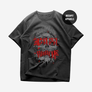 Puede incluir: Camiseta gris oscuro con un gráfico de calavera y texto rojo "SCARY ROCK". La calavera tiene un mohawk y un diseño roto. La camiseta tiene cuello redondo y mangas cortas. El logotipo de la marca "MOSHPIT APPARELS" está en la parte superior derecha.