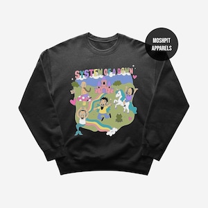 Könnte beinhalten: Schwarzes Sweatshirt mit einer farbenfrohen Grafik mit dem Text "SYSTEM OF A DOWN". Das Design umfasst Cartoonfiguren, ein Schloss, einen Regenbogen und ein Einhorn. Der Markenname "MOSHPIT APPARELS" ist ebenfalls sichtbar.