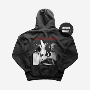 May include: Charcoal grey hoodie with a black and white face graphic and red text reading "my bloody valentine". The hoodie also features the brand name "MOSHPIT APPARELS" on a black circular badge. A hooded sweatshirt.