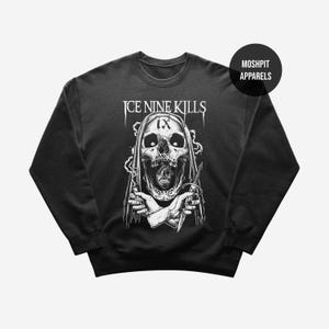 May include: Black crew neck sweatshirt with a white graphic of a skull holding a knife, and the text "ICE NINE KILLS". The skull is hooded. The brand name "MOSHPIT APPARELS" is on the upper right. A dark, gothic design.
